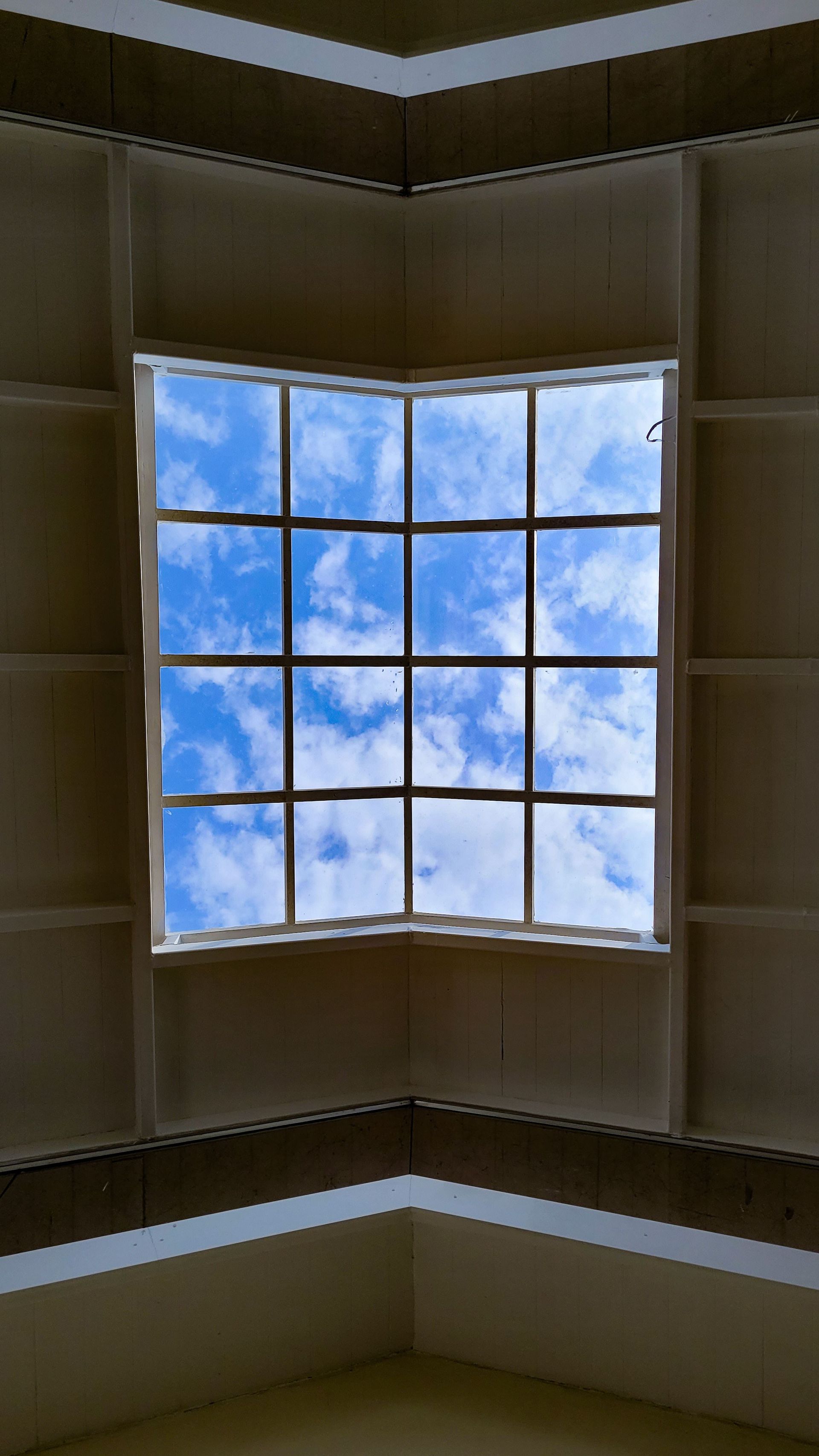Modern interior skylight showing a beautiful blue sky with scattered clouds.