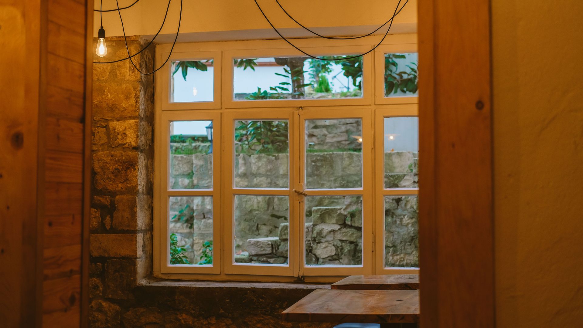 Warm and inviting indoor setting featuring rustic elements and a view through a large window.